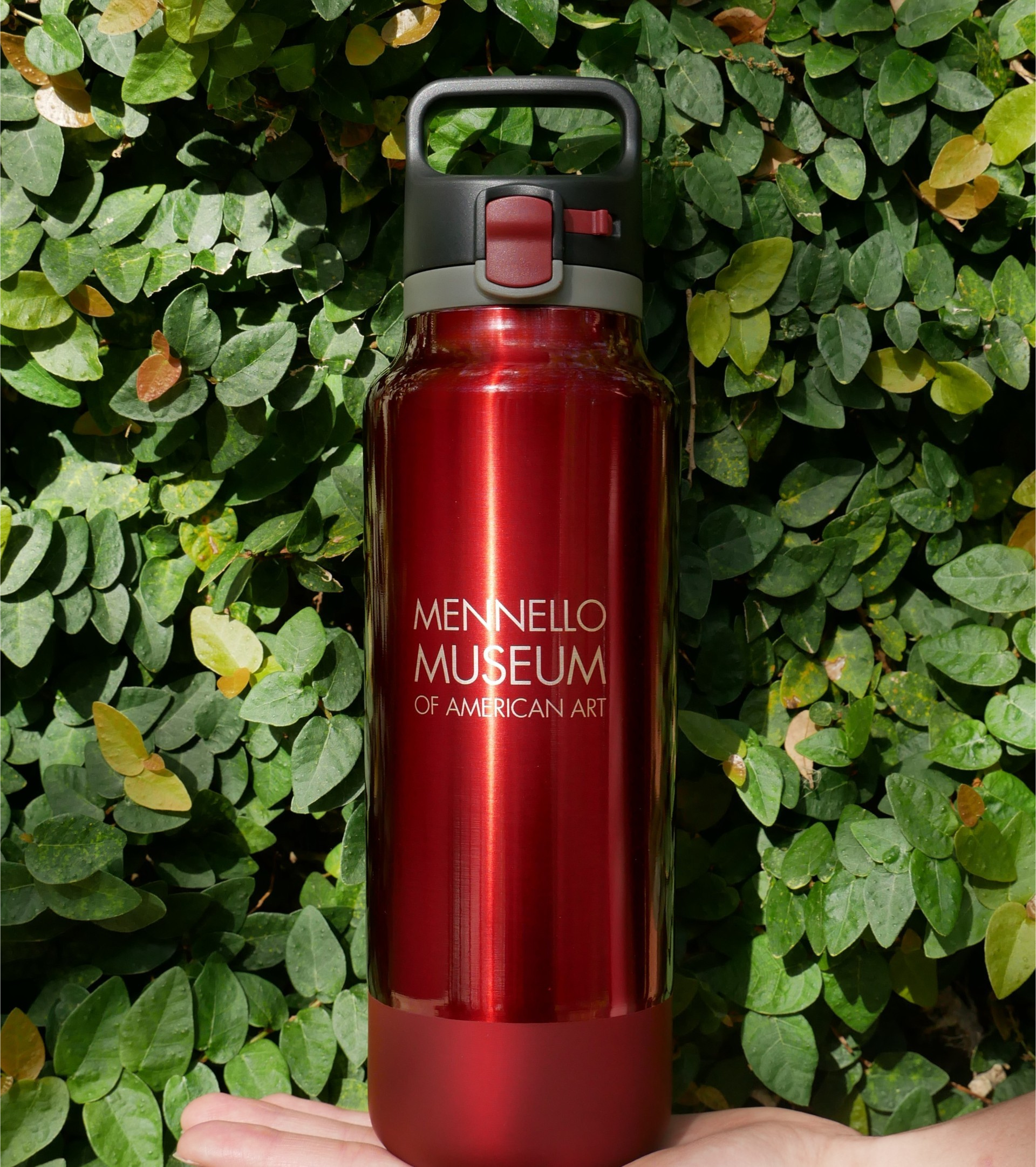 A red metal water bottle with a white Mennello Museum of American Art logo